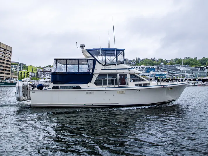 Bleu Fish Yacht Photos Pics 1988 Tollycraft 44 CPMY yacht cruising on a calm waterway with cityscape background.