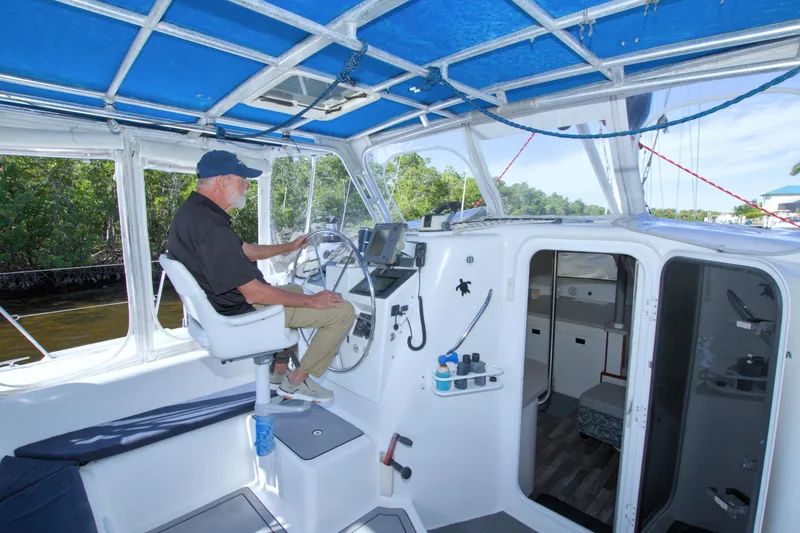 Scout Yacht Photos Pics Man steering a 1996 Manta 40 sailboat under a blue canopy.
