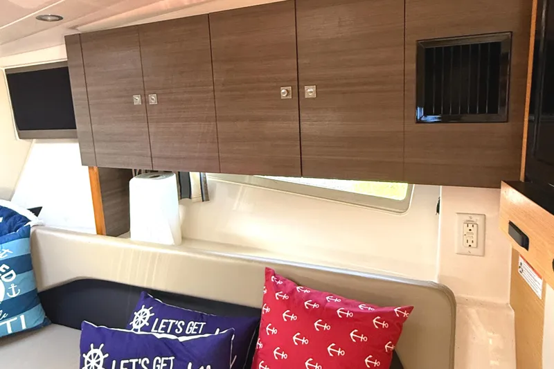  Yacht Photos Pics Interior of 2013 Pursuit 365i Sport Coupe with wooden cabinets and nautical-themed cushions.