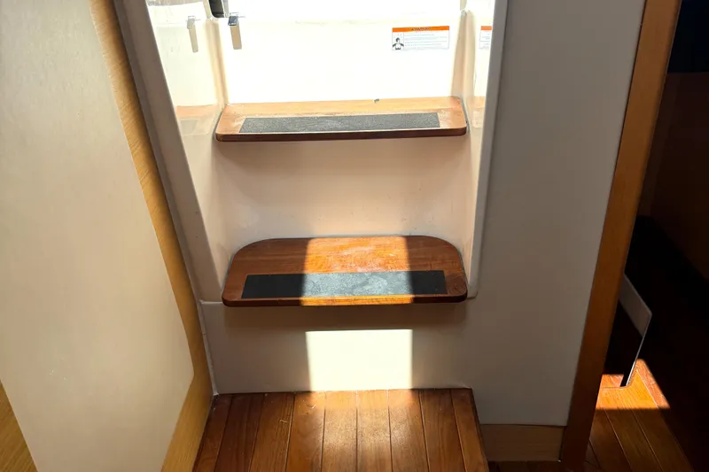  Yacht Photos Pics Interior wooden steps of a 2013 Pursuit 365i Sport Coupe yacht, illuminated by sunlight.