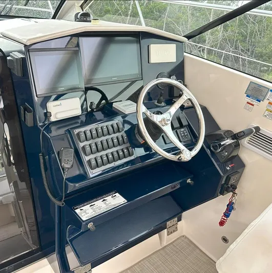  Yacht Photos Pics Control panel of a 2013 Pursuit 365i Sport Coupe with steering wheel and navigation screens.