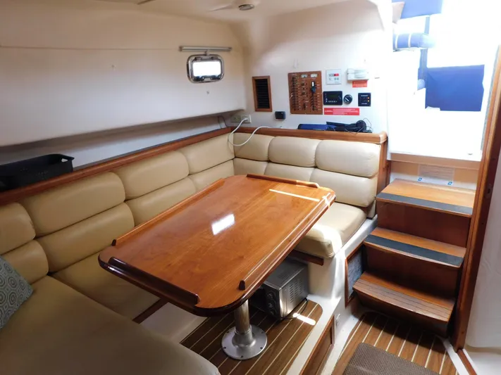 Calm Yacht Photos Pics 2005 Mainship 34 Rum Runner interior with beige seating, wooden table, and stairs.