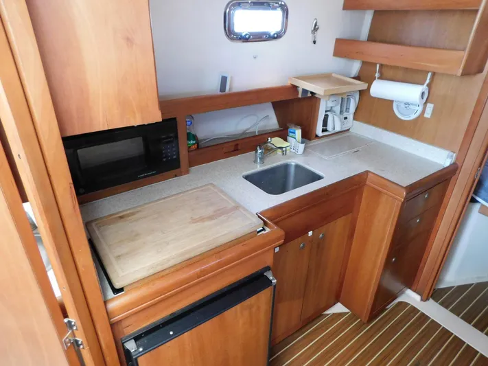 Calm Yacht Photos Pics 2005 Mainship 34 Rum Runner galley with wood cabinetry, sink, microwave, and compact fridge.