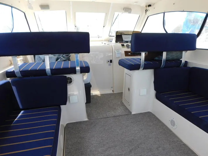 Calm Yacht Photos Pics Interior of 2005 Mainship 34 Rum Runner with blue seating and spacious layout.