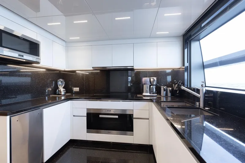 Ambar Yacht Photos Pics Modern kitchen interior on 2020 Sanlorenzo SLA120A yacht, featuring sleek black and white design.