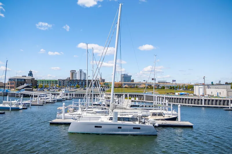 Navitas Yacht Photos Pics 2019 Itacatamarans 14.99 docked in a marina with cityscape background.