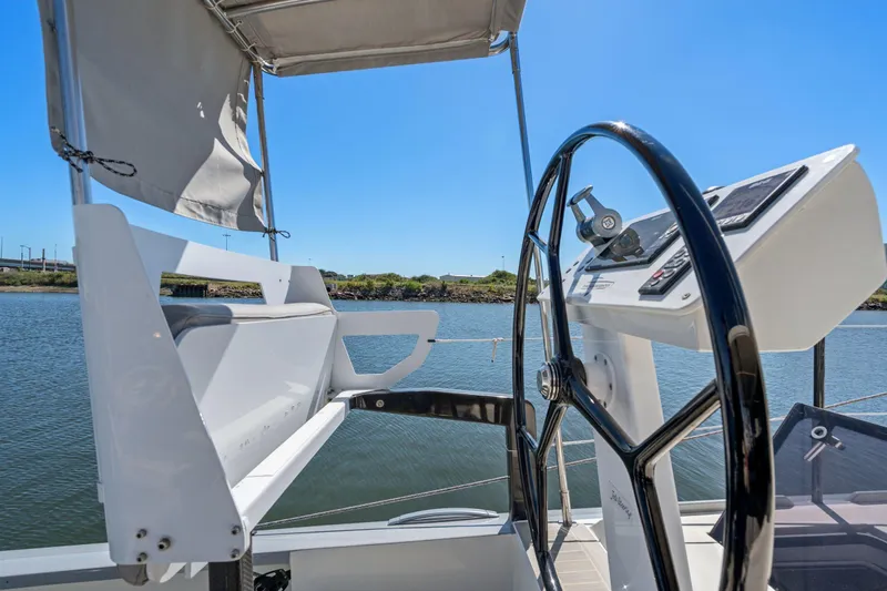 Navitas Yacht Photos Pics Helm of 2019 Itacatamarans 14.99 catamaran with steering wheel and controls, on calm water.