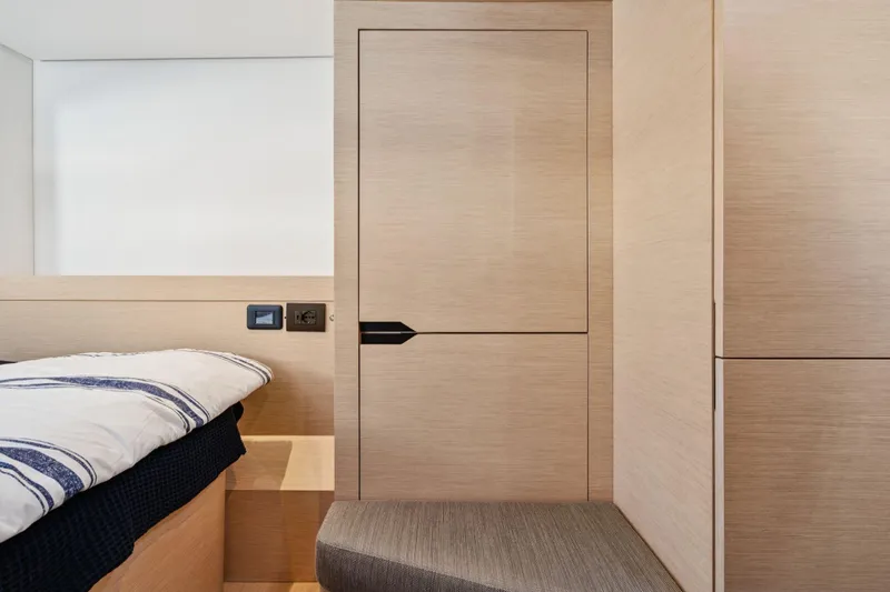 Navitas Yacht Photos Pics Interior of 2019 Itacatamarans 14.99, featuring modern wood paneling and cozy bedding.