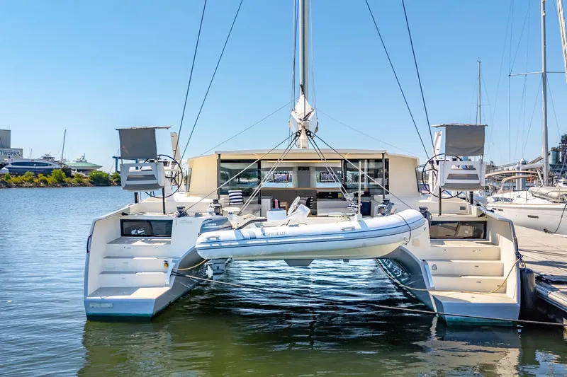 Navitas Yacht Photos Pics 2019 Itacatamarans 14.99 catamaran docked with inflatable boat, sunny marina setting.