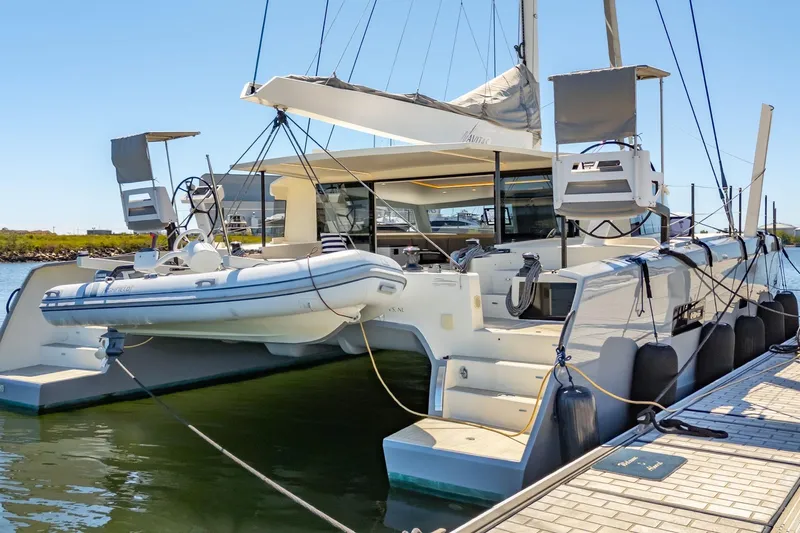 Navitas Yacht Photos Pics 2019 Itacatamarans 14.99 catamaran docked with inflatable boat, sunny day.