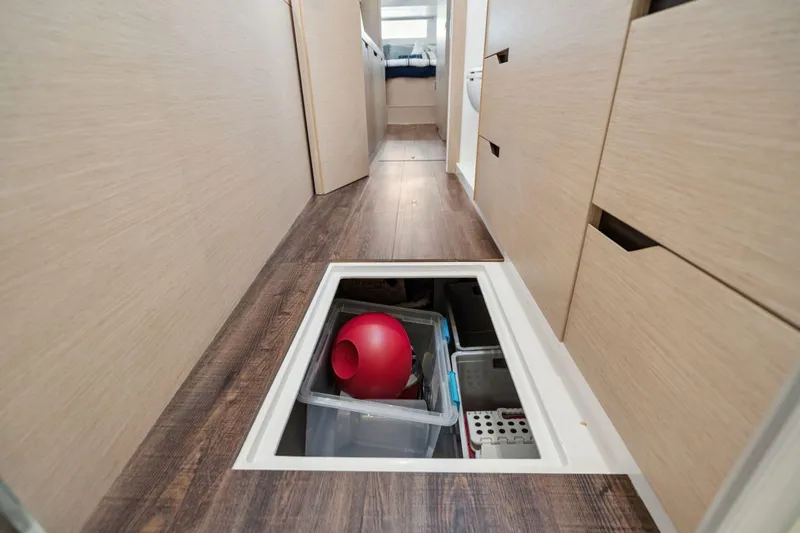 Navitas Yacht Photos Pics Hidden storage compartment in 2019 Itacatamarans 14.99, featuring wooden flooring and organized containers.