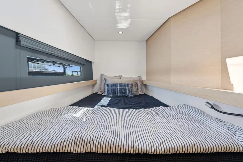 Navitas Yacht Photos Pics Cozy cabin interior of 2019 Itacatamarans 14.99 with striped bedding and window view.