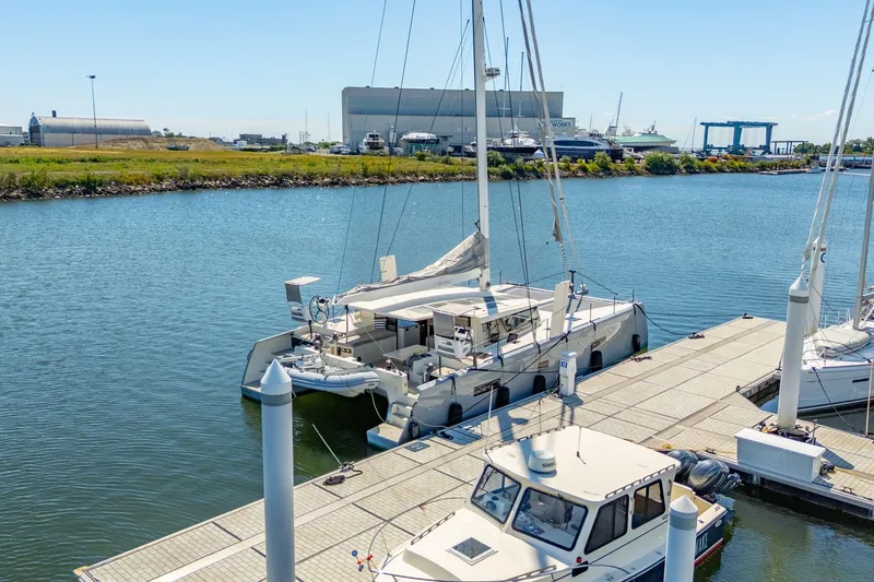 Navitas Yacht Photos Pics 2019 Itacatamarans 14.99 docked at marina, surrounded by calm water and industrial backdrop.