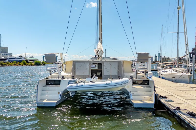 Navitas Yacht Photos Pics 2019 Itacatamarans 14.99 catamaran docked at marina, rear view with dinghy attached.