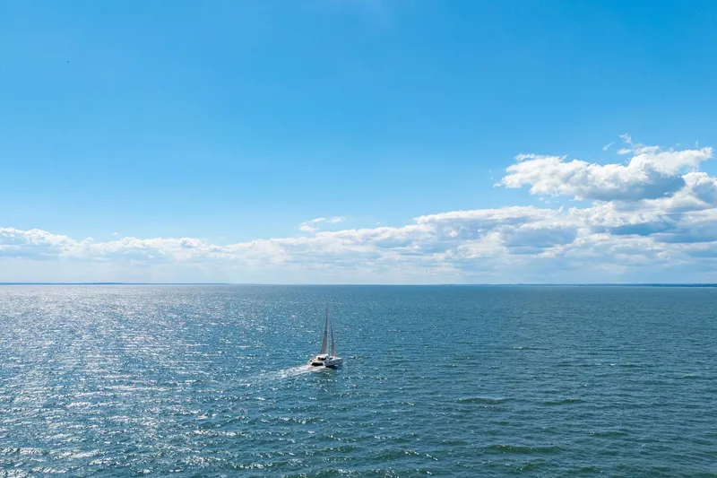 Navitas Yacht Photos Pics 2019 Itacatamarans 14.99 sailing on a vast, sunny ocean under a clear blue sky.