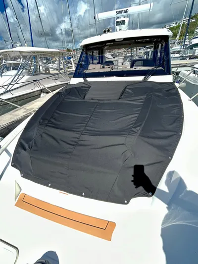  Yacht Photos Pics 2025 Boston Whaler 365 Conquest boat with black cover, docked under a cloudy sky.