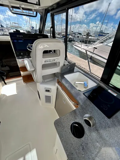  Yacht Photos Pics 2025 Boston Whaler 365 Conquest interior with helm, sink, and countertop in marina setting.