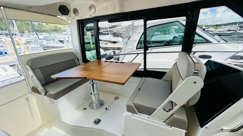  Yacht Photos Pics 2025 Boston Whaler 365 Conquest interior with seating and wooden table, docked at marina.