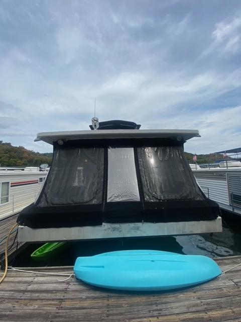 1985 Arc houseboat with black windows, docked with a blue kayak.