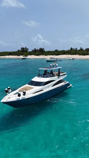  Yacht Photos Pics Luxury Fairline Squadron 58 yacht, 2006 model, cruising in turquoise waters near a sandy beach.
