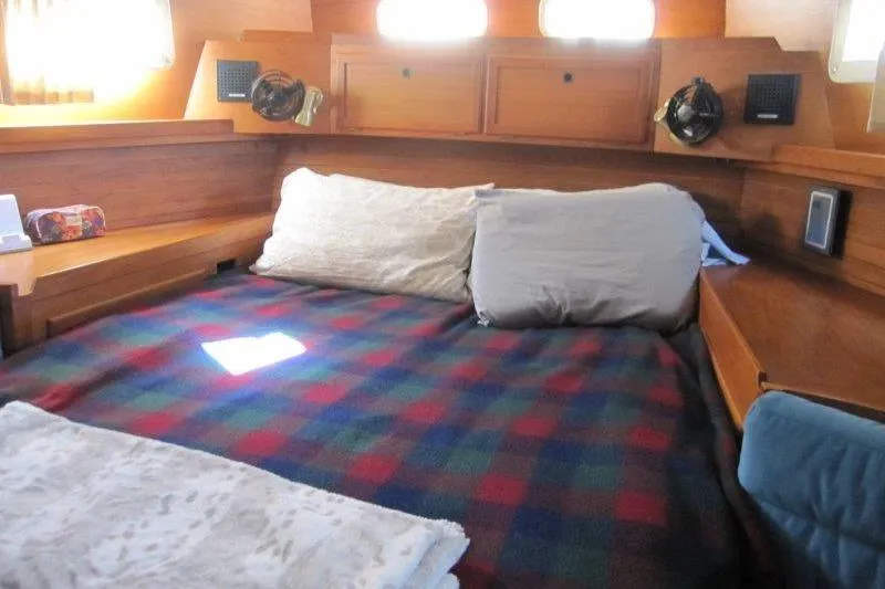 Bella Yacht Photos Pics Cozy cabin interior of 1983 Nauticat 43 sailboat with plaid bedding and wooden furnishings.