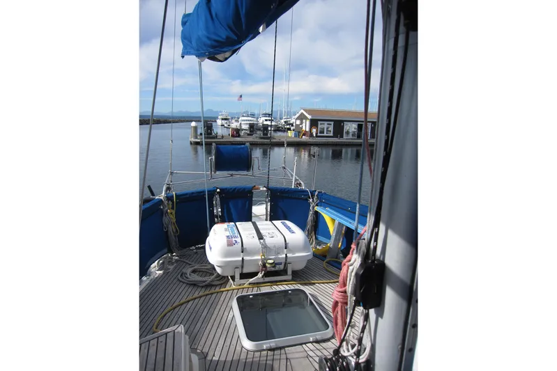 Bella Yacht Photos Pics 1983 Nauticat 43 sailboat deck view at marina, featuring blue canopy and lifeboat.