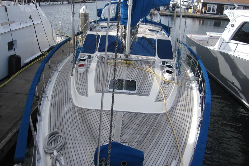 Bella Yacht Photos Pics 1983 Nauticat 43 sailboat docked, featuring a sleek wooden deck and blue accents.
