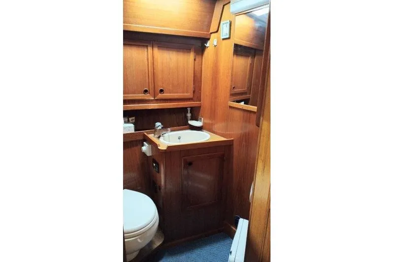 Bella Yacht Photos Pics 1983 Nauticat 43 yacht bathroom with wooden cabinetry and compact sink.