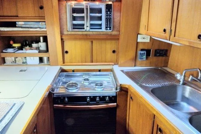 Bella Yacht Photos Pics 1983 Nauticat 43 yacht kitchen with stove, sink, and wooden cabinetry.