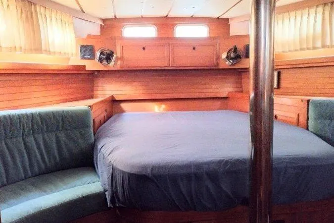 Bella Yacht Photos Pics Cozy cabin interior of 1983 Nauticat 43 sailboat with wood paneling and blue bedding.