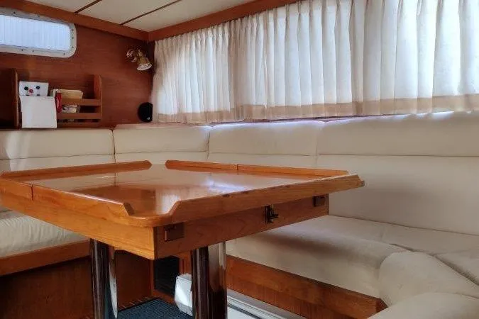 Bella Yacht Photos Pics Interior of 1983 Nauticat 43 yacht with wooden table and cream seating.