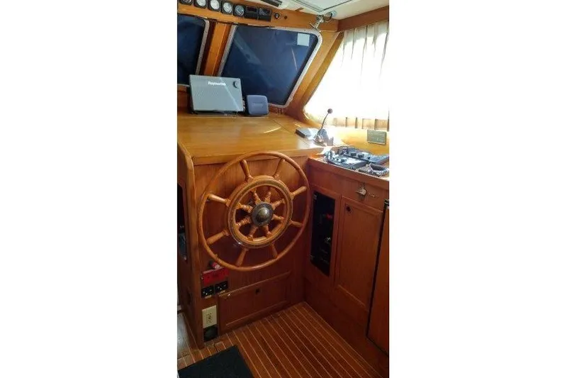 Bella Yacht Photos Pics Interior helm of 1983 Nauticat 43 sailboat with wooden steering wheel and navigation equipment.