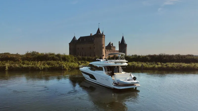  Yacht Photos Pics Luxurious 2019 Prestige 590 yacht cruising near a historic castle on a serene river.