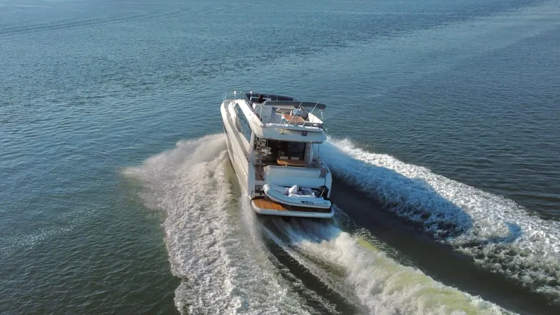  Yacht Photos Pics Luxurious 2019 Prestige 590 yacht cruising on open water, creating a dynamic wake.