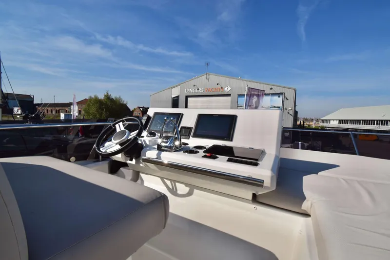  Yacht Photos Pics Helm of 2019 Prestige 590 yacht with modern navigation equipment, docked at a marina.