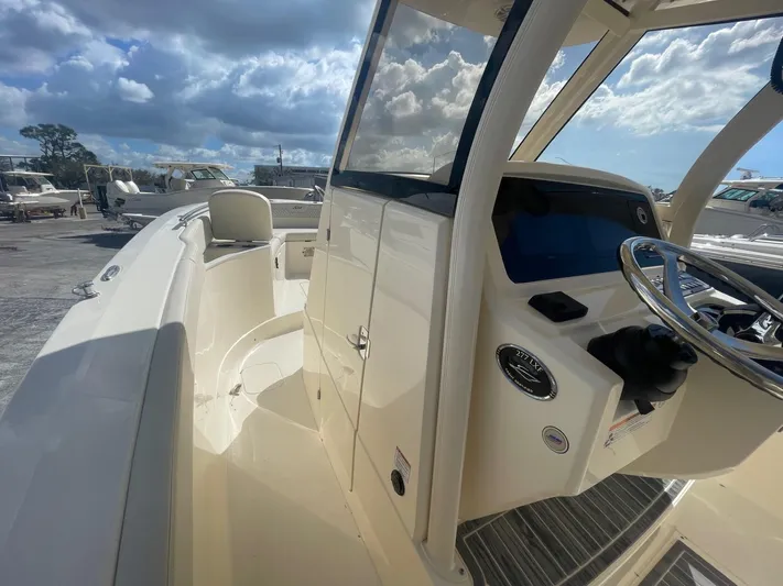  Yacht Photos Pics 2025 Scout 277 LXF boat interior with steering wheel and dashboard under a cloudy sky.