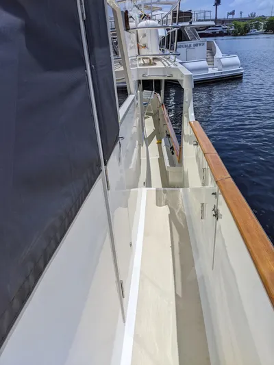 Pura Vida III Yacht Photos Pics 1999 Grand Alaskan Pilothouse yacht side deck with wooden railings, docked at a marina.