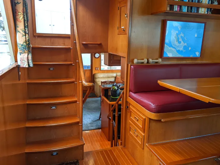 Pura Vida III Yacht Photos Pics Interior of 1999 Grand Alaskan Pilothouse yacht with wooden stairs and seating area.