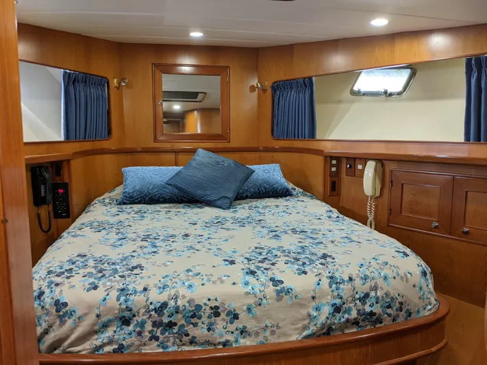 Pura Vida III Yacht Photos Pics 1999 Grand Alaskan Pilothouse bedroom with floral bedding, wooden cabinetry, and porthole windows.
