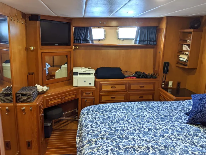 Pura Vida III Yacht Photos Pics 1999 Grand Alaskan Pilothouse bedroom with wood cabinetry, TV, and blue floral bedspread.