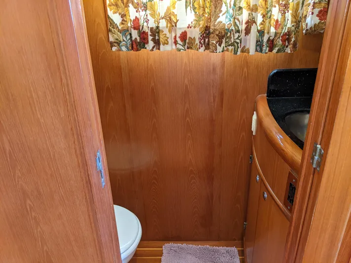 Pura Vida III Yacht Photos Pics 1999 Grand Alaskan Pilothouse bathroom with wooden paneling and floral curtains.