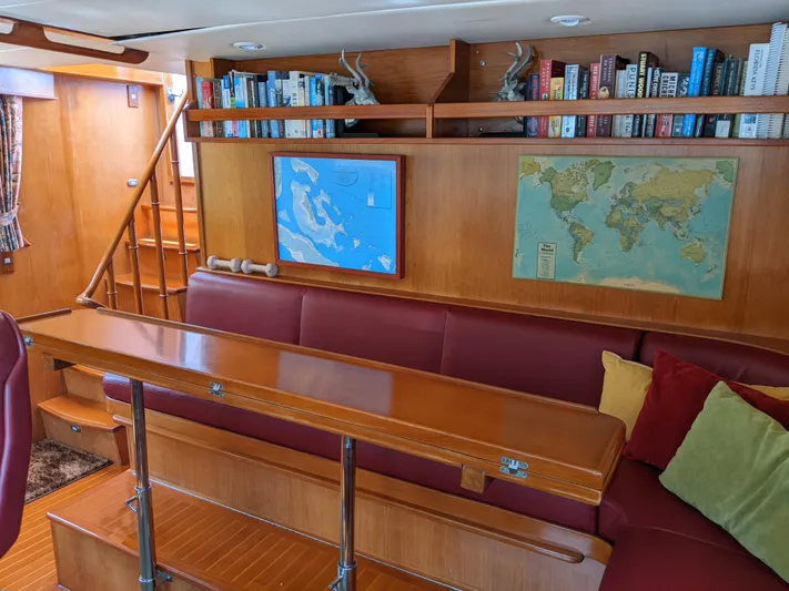 Pura Vida III Yacht Photos Pics 1999 Grand Alaskan Pilothouse interior with red seating, wooden table, maps, and bookshelves.