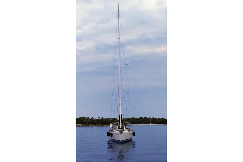 Vanish 2 Yacht Photos Pics Sailing yacht Nautor Swan 56, 1999 model, anchored on calm water under a cloudy sky.