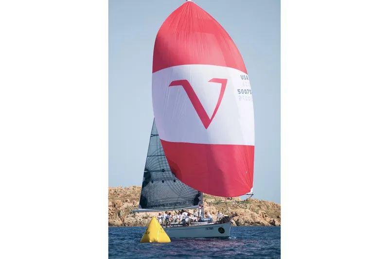 Vanish 2 Yacht Photos Pics Sailing yacht Nautor Swan 56 (1999) with red and white spinnaker in open water.