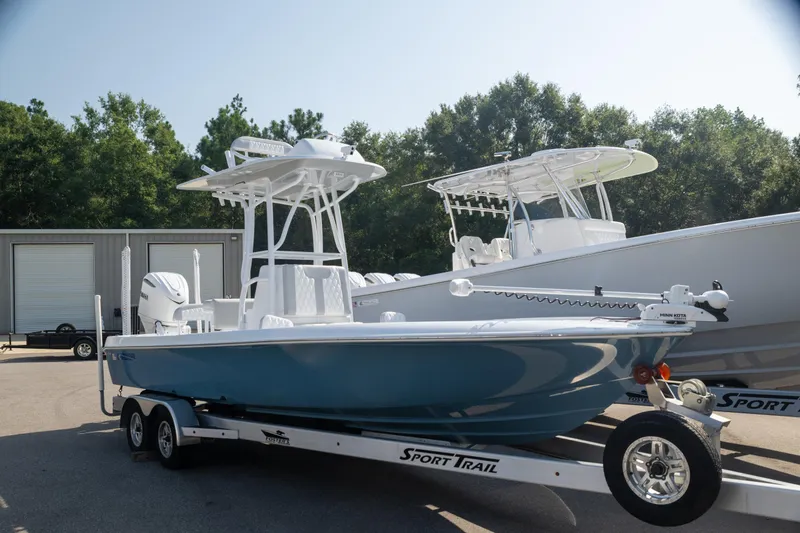  Yacht Photos Pics 2025 Contender 26 Bay boat on trailer, parked outdoors, with trees and buildings in background.