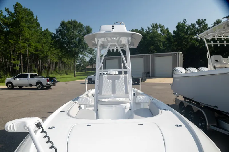  Yacht Photos Pics 2025 Contender 26 Bay boat in a parking lot, surrounded by trees and vehicles.