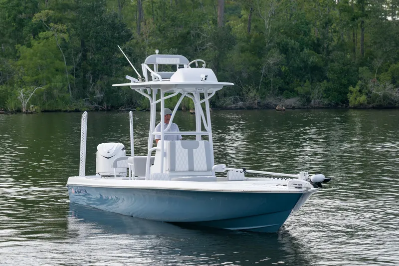  Yacht Photos Pics 2025 Contender 26 Bay boat on calm water, surrounded by lush greenery.