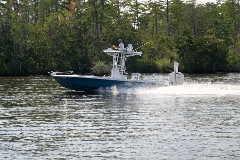  Yacht Photos Pics 2025 Contender 26 Bay boat cruising on a calm river with lush greenery.