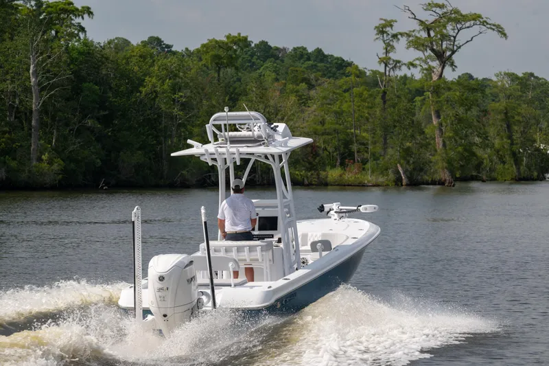  Yacht Photos Pics 2025 Contender 26 Bay boat cruising on a scenic river with lush greenery.