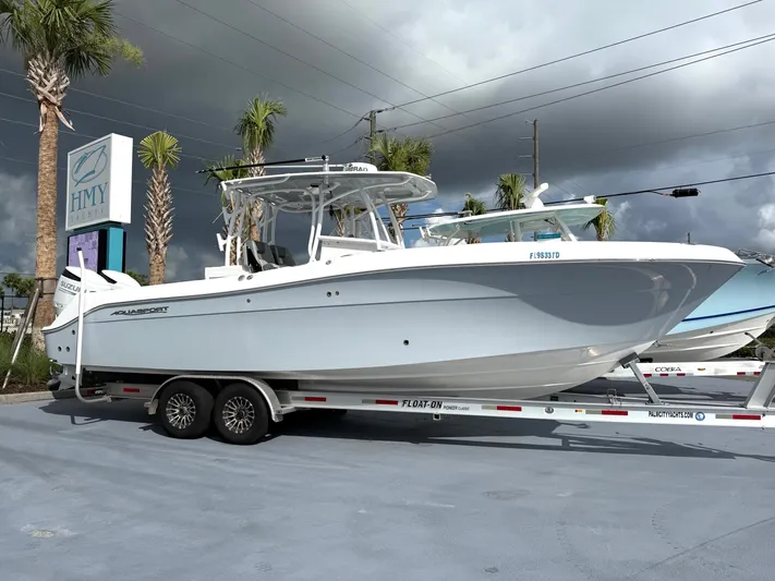  Yacht Photos Pics 2022 Aquasport 3000CC boat on trailer at HMY Yachts dealership, under cloudy sky.